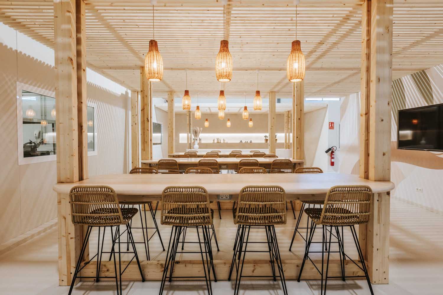 Dining table with wood bar stools beneath pendant lights along a wood-slat wall