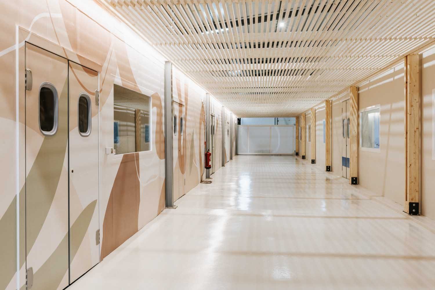 Corridor with patterned sliding doors beneath a slatted wood ceiling