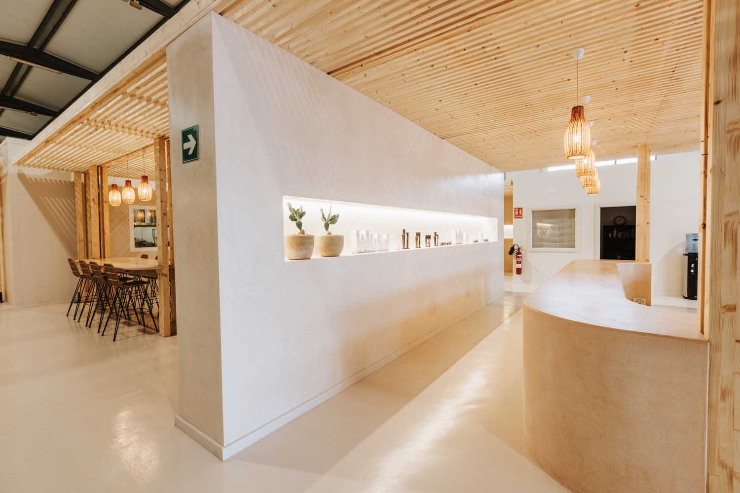 Curved reception desk beneath a wood-slat canopy with backlit product shelving