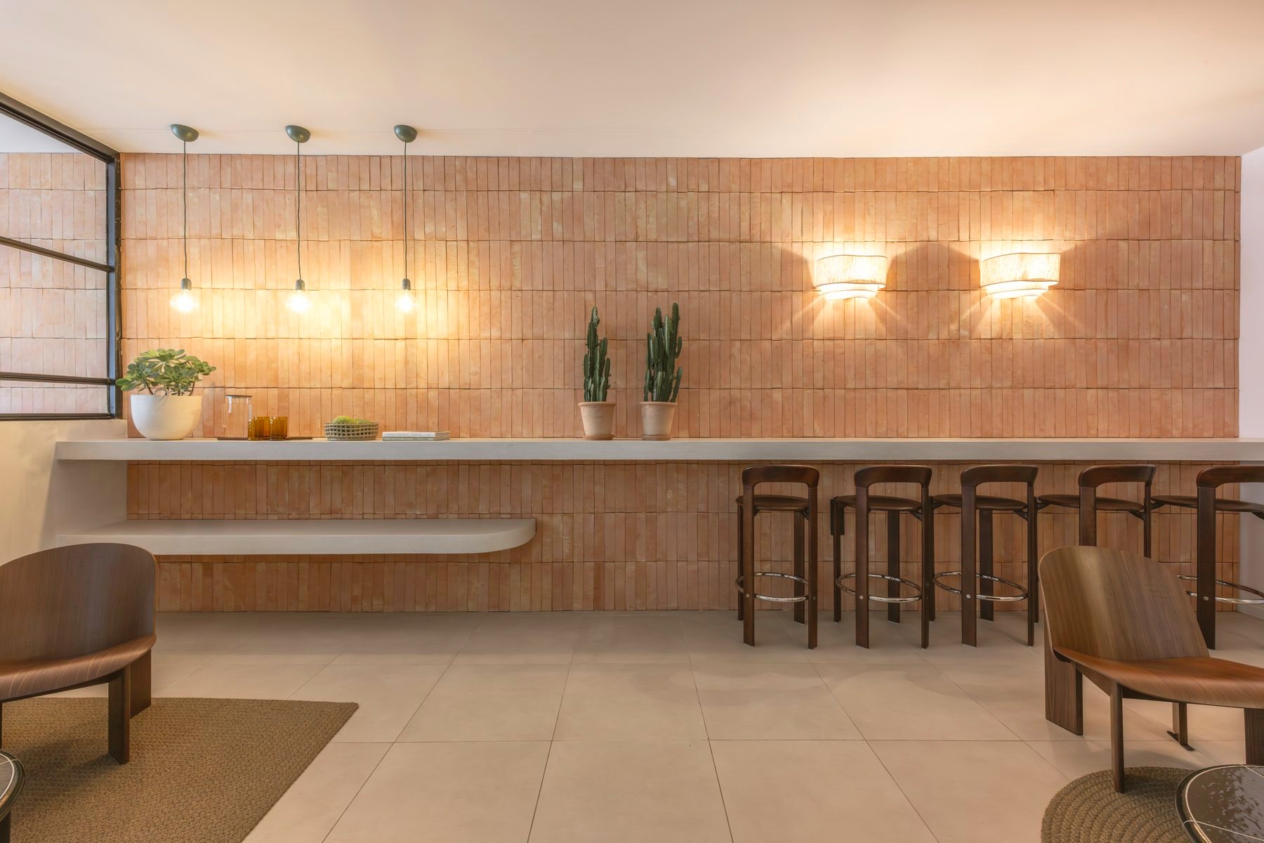 Reception desk along the terracotta tiled wall beneath pendant lighting