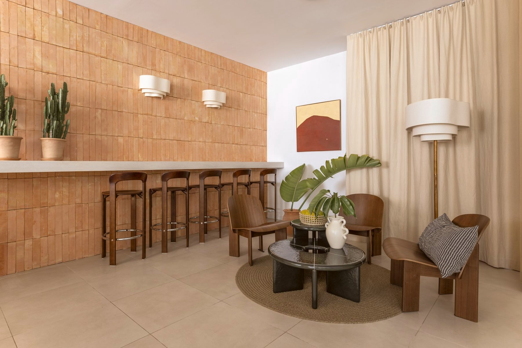 Lounge seating nook beside a wood-slat wall with a framed landscape painting