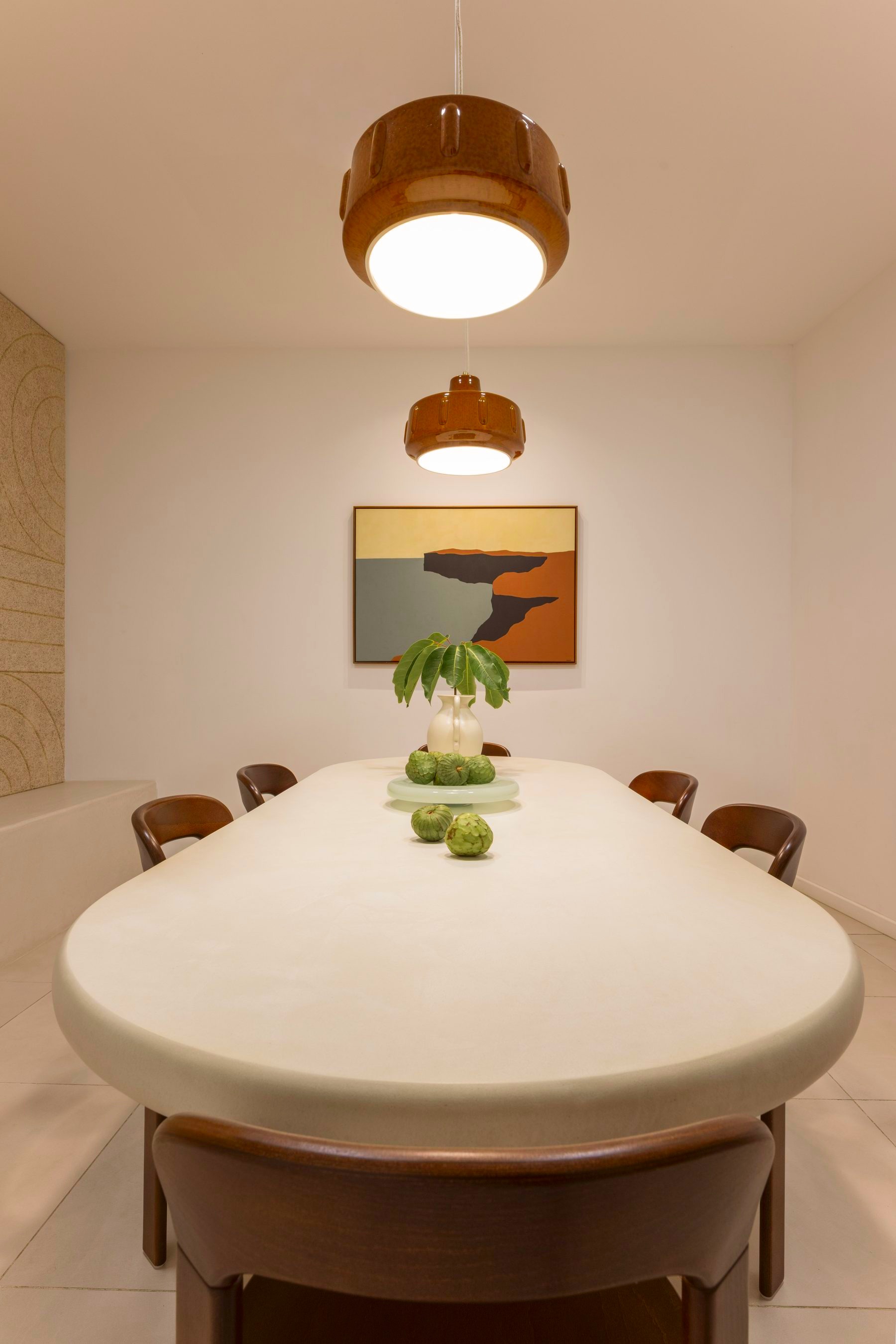Oval meeting table with pendant lights and framed coastal art