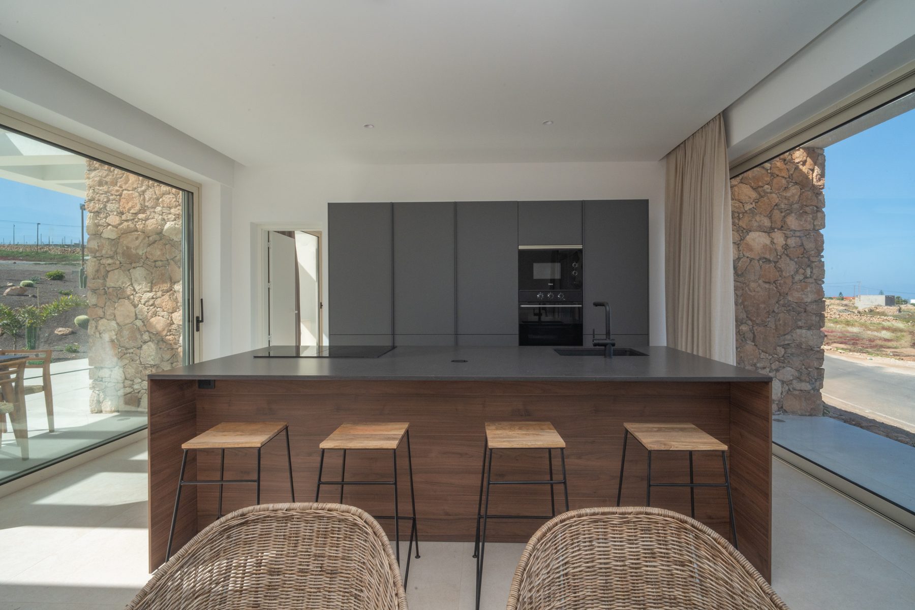 Kitchen island with wood bar stools beside a stone accent wall