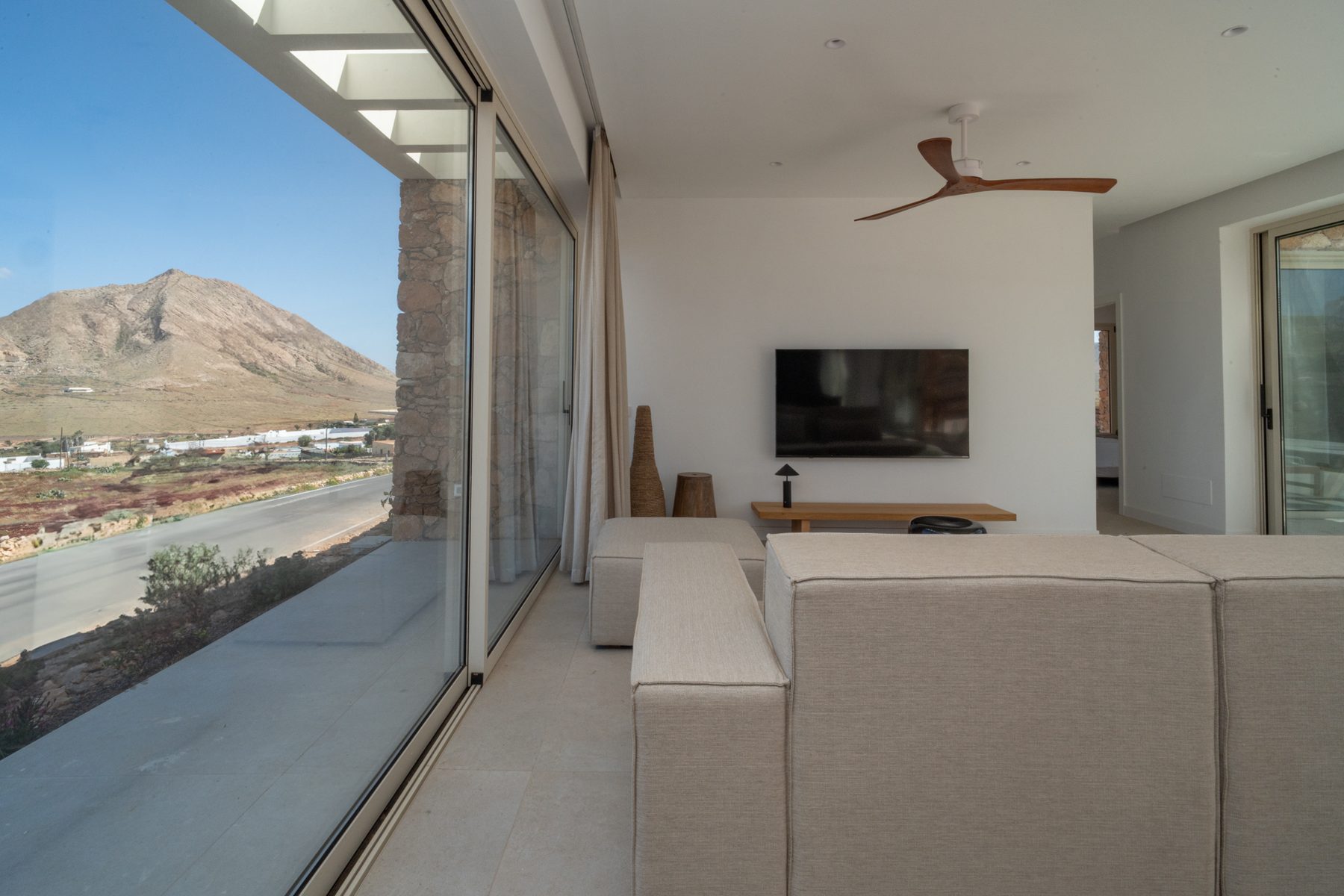 Living room with a wall-mounted TV and a mountain-view window
